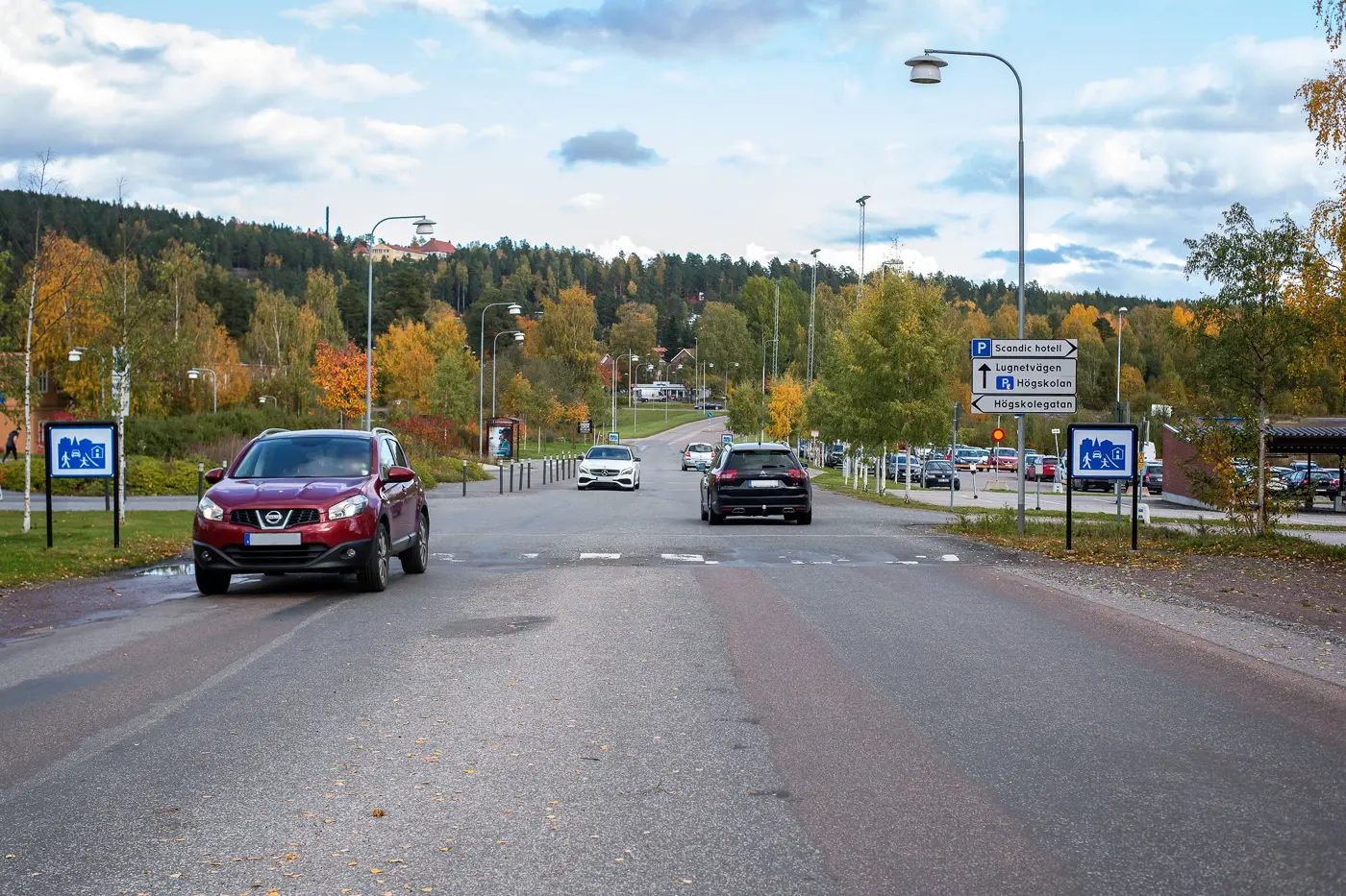 Bilar kör på en väg och passerar en skylt som markerar gångfartsområde.