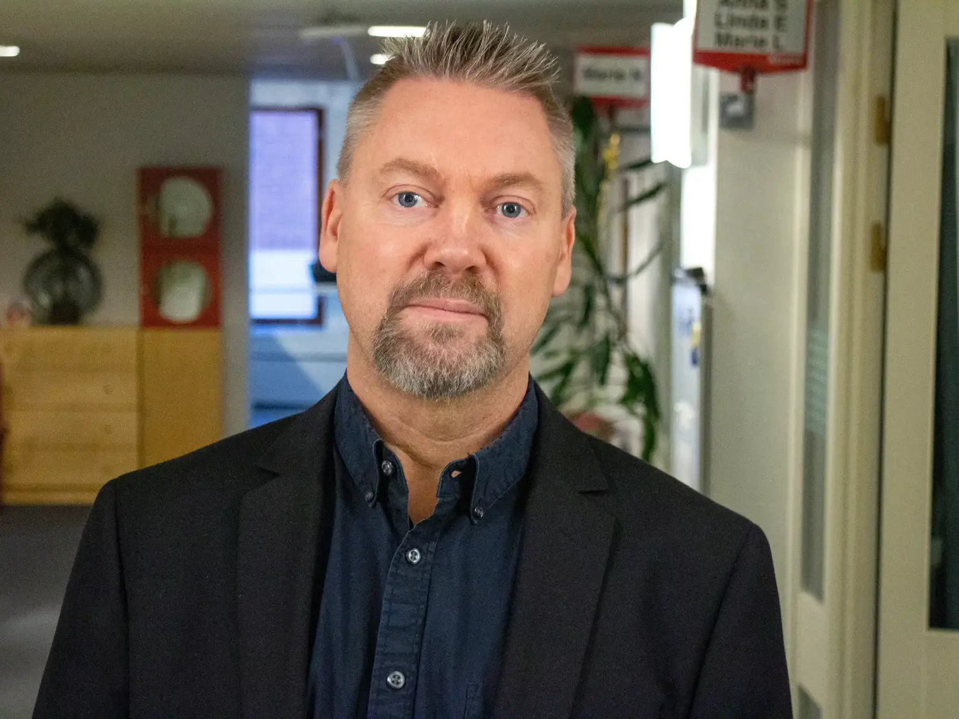 En man med blå skjorta och svart kavaj.