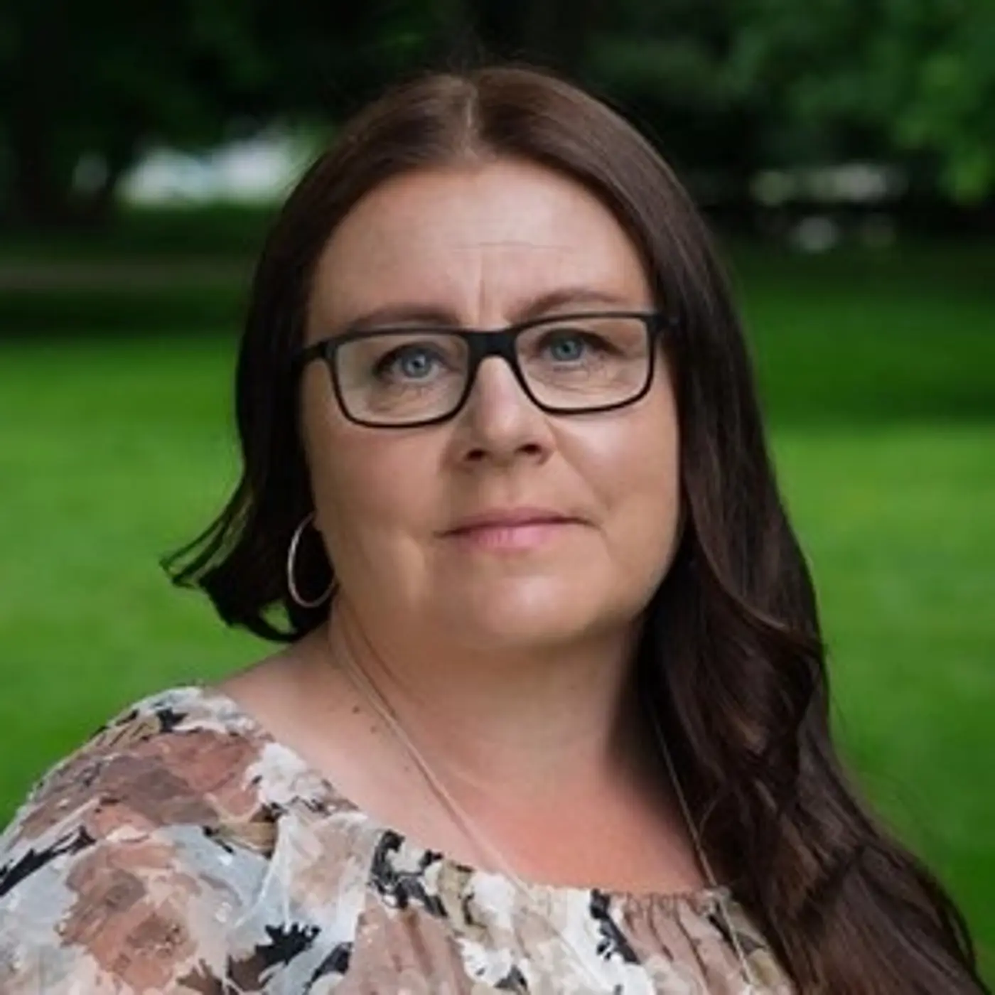 En kvinna med långt mörkbrunt hår och glasögon.