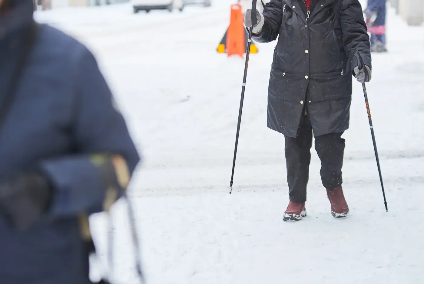 Person promenerar med gåstavar på snö.
