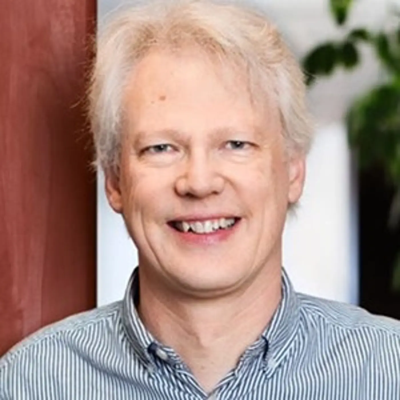 En leende man med blå-vitrandig skjorta.