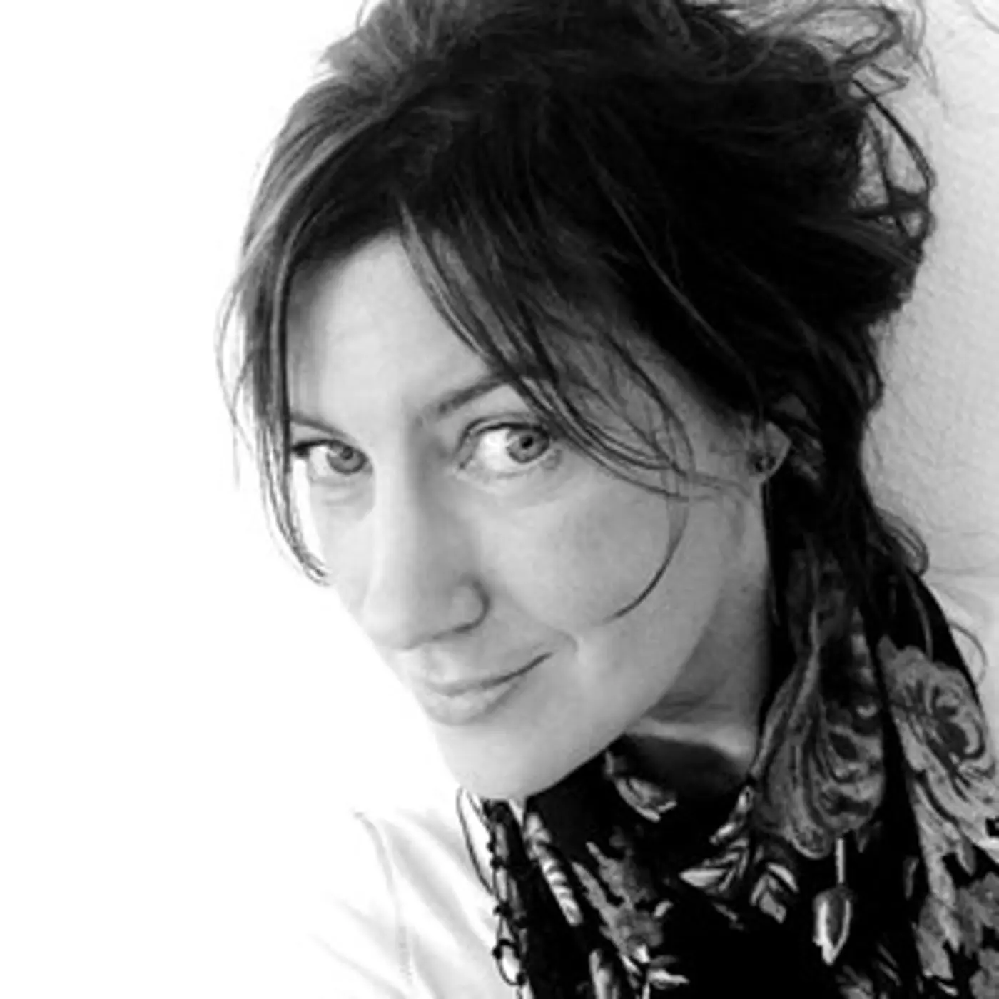 En leende kvinna med uppsatt hår och scarf.