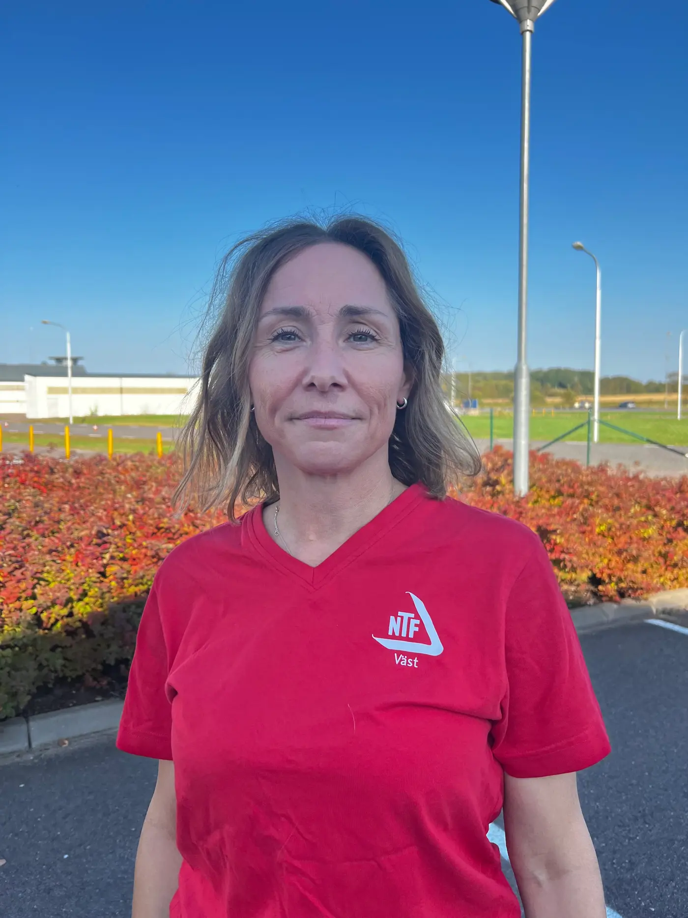 En leende kvinna med axellångt hår och röd t-shirt.