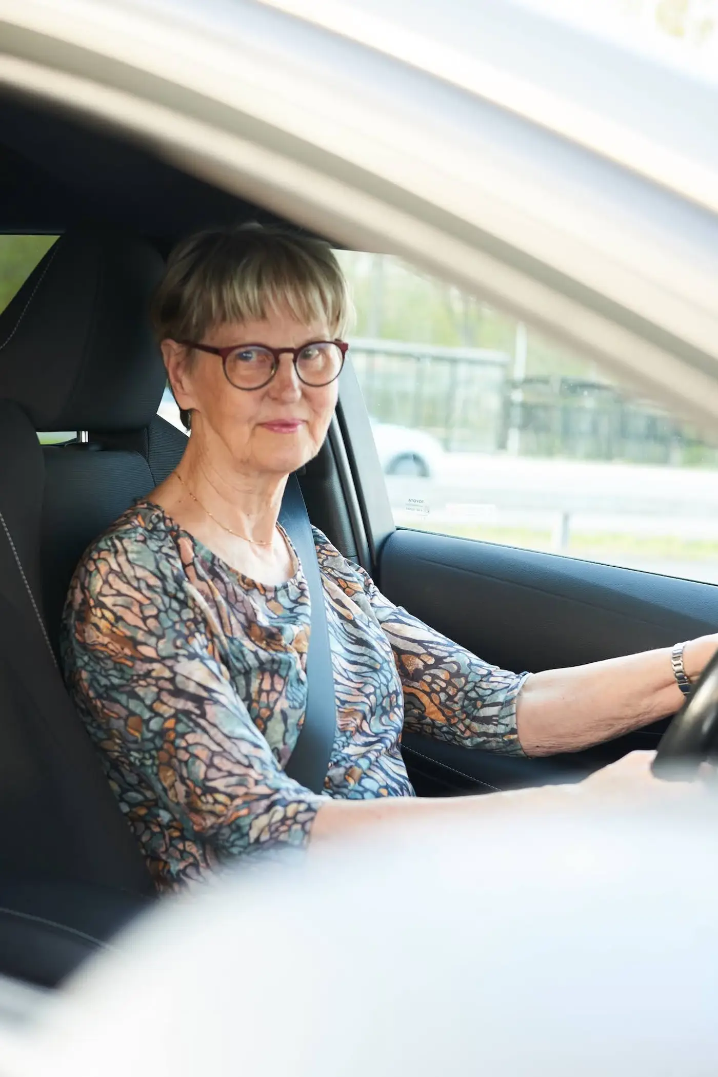 En äldre kvinna kör bil.