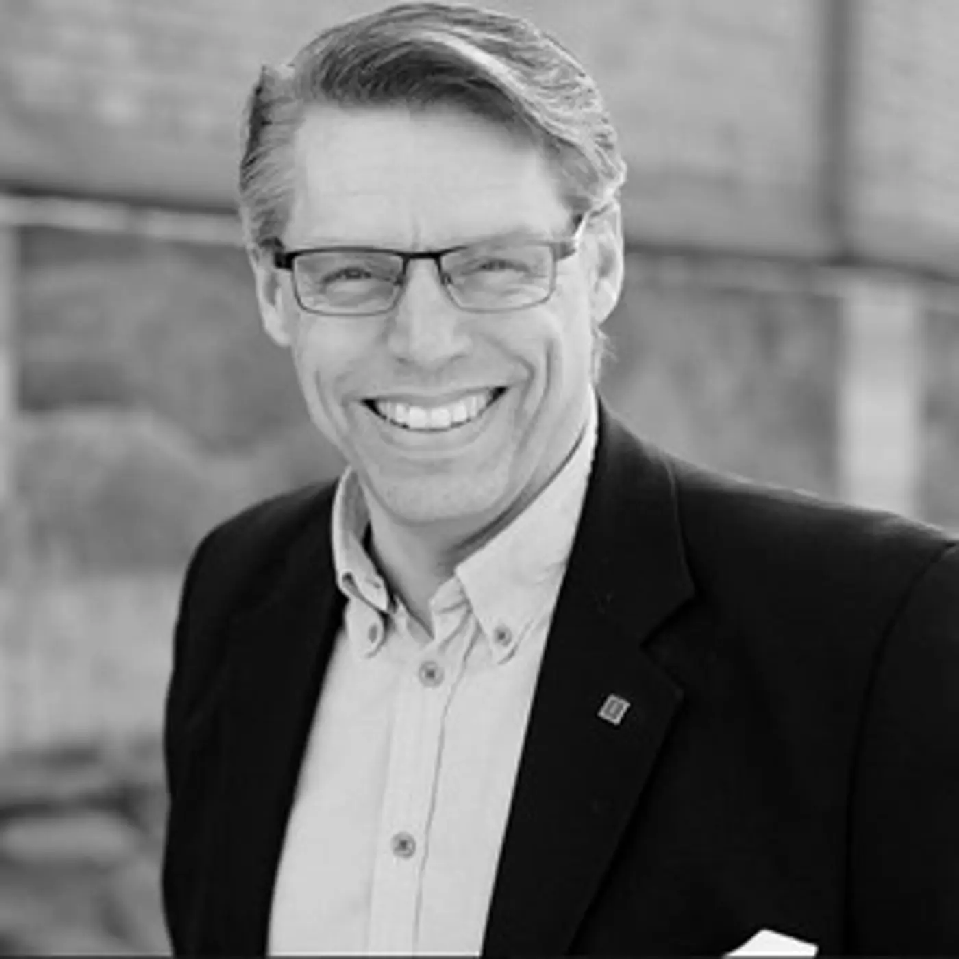 En leende man med glasögon och kavaj.