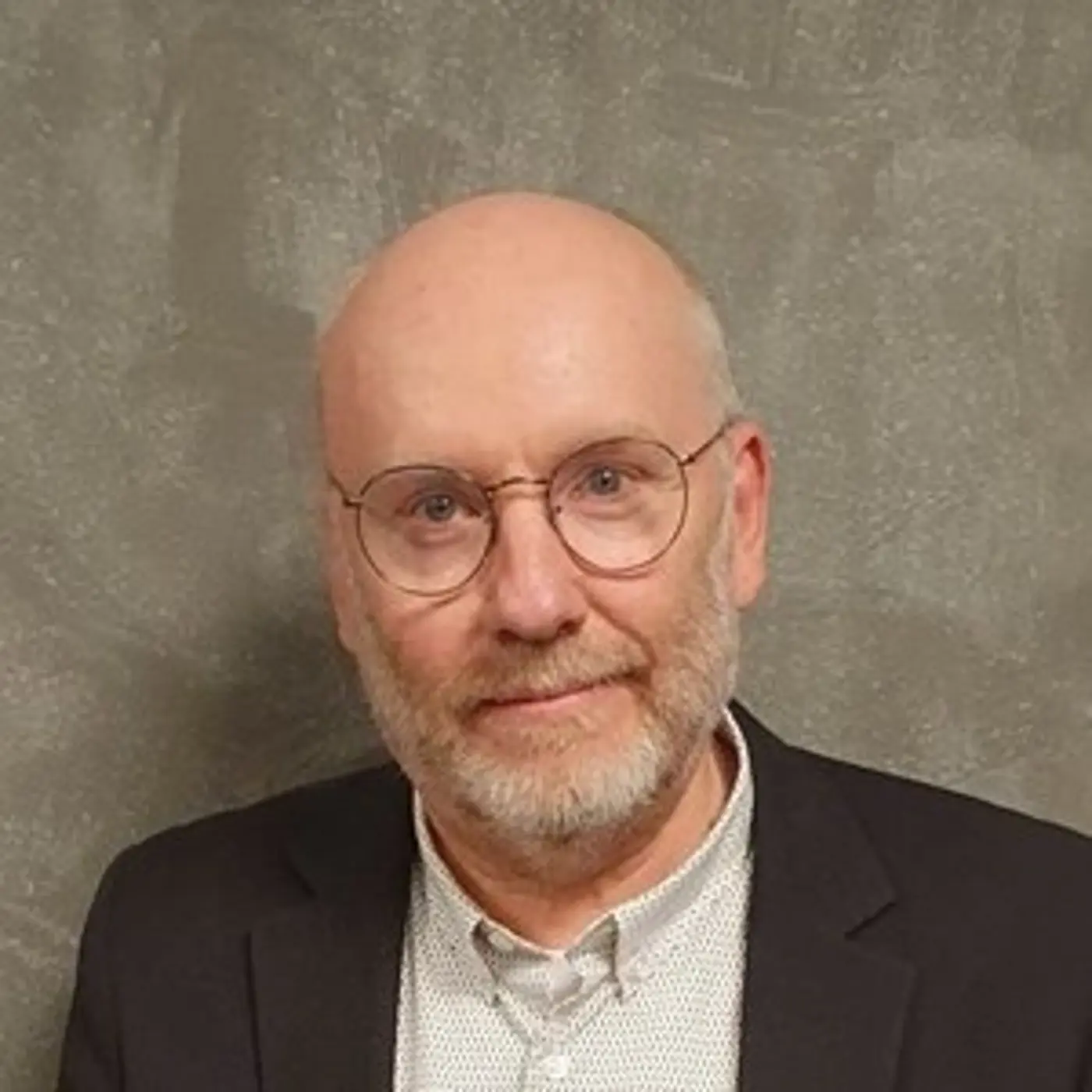 En man med glasögon, skjorta och kavaj.