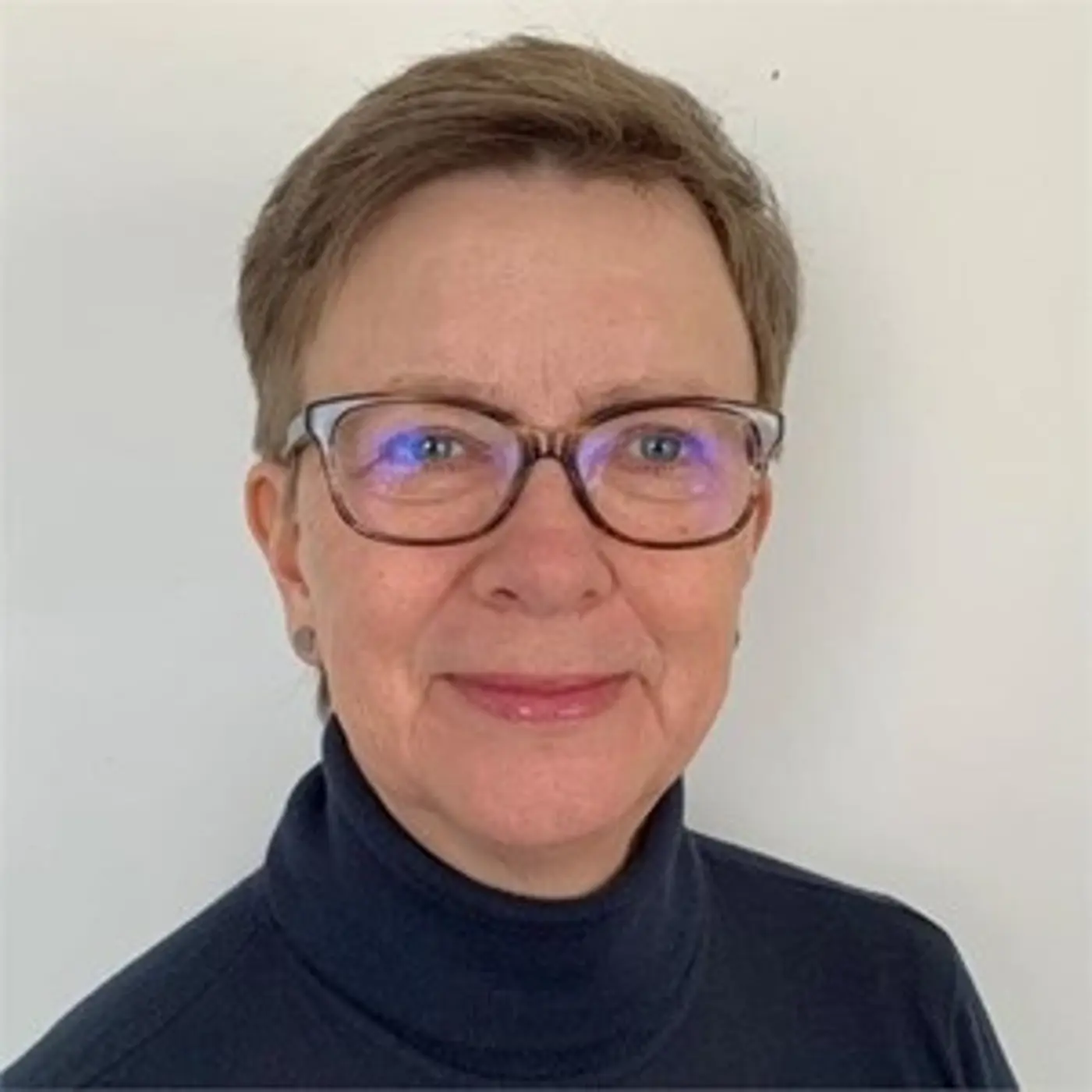 En leende kvinna med glasögon och mörk polotröja.