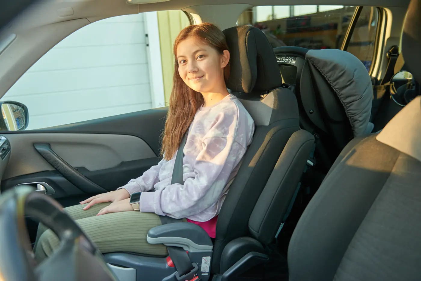 Ett barn sitter på bälteskudde i framsätet på en bil.