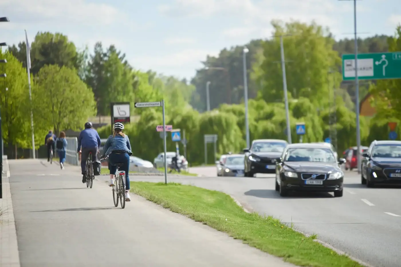 Cyklister kör på cykelväg som löper längsmed en trafikerad bilväg 