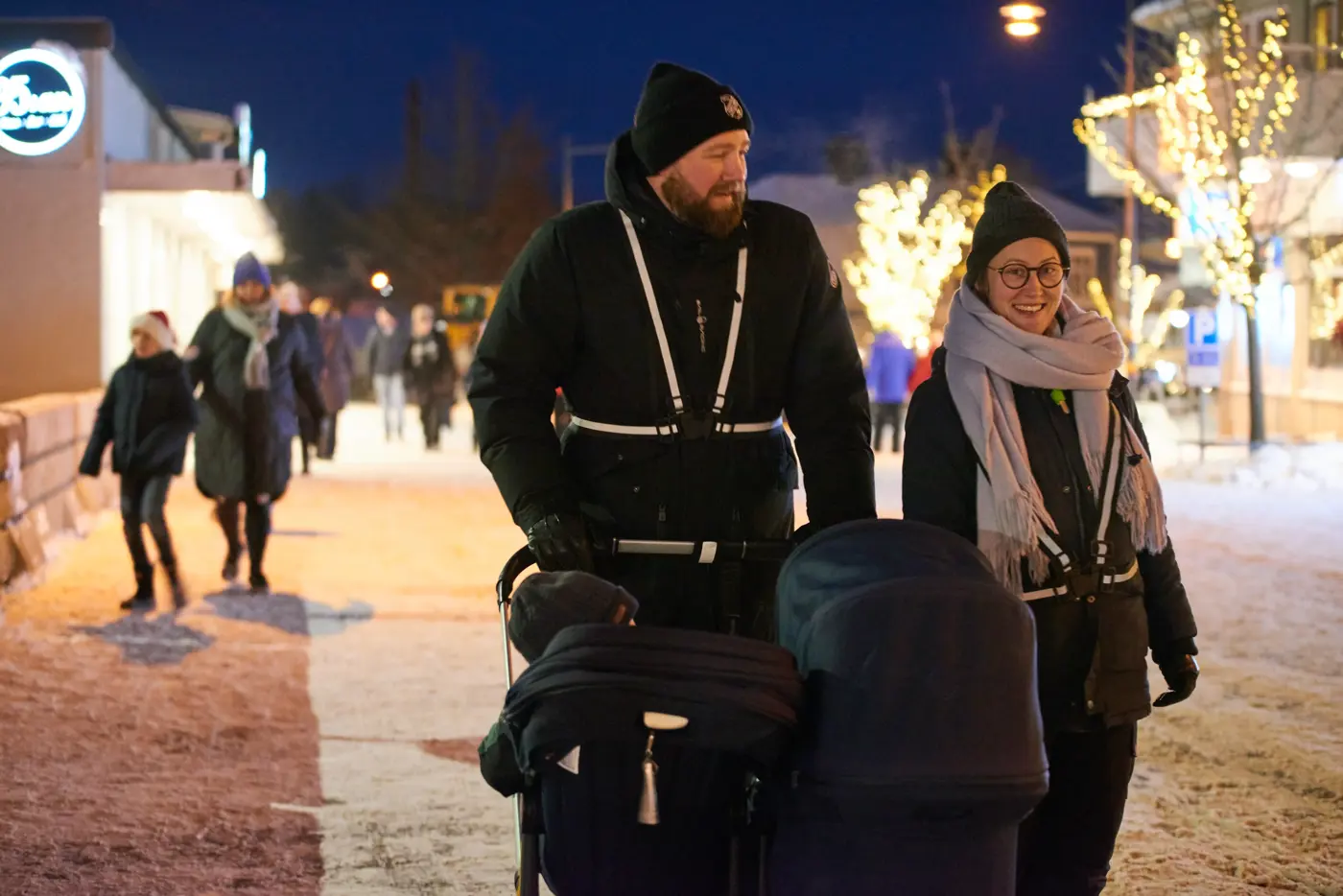En familj med reflexer som är ute och går med barnvagn i mörker.