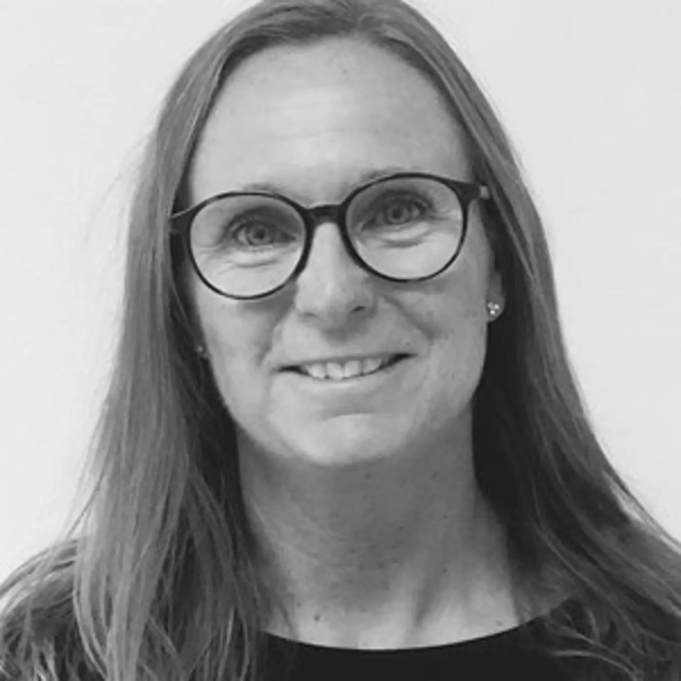 En leende kvinna med långt hår och glasögon.