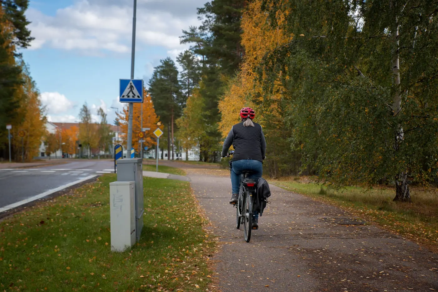 En cyklist kör på en gång-och cykelbana som löper längs med en bilväg.