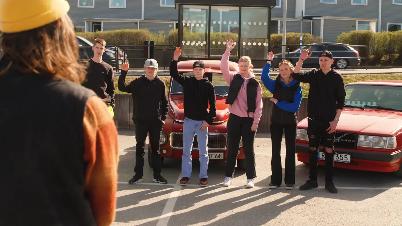 Bild på flera ungdomar som räcker upp händerna, bakom står deras mopedbilar oh a-traktorer.