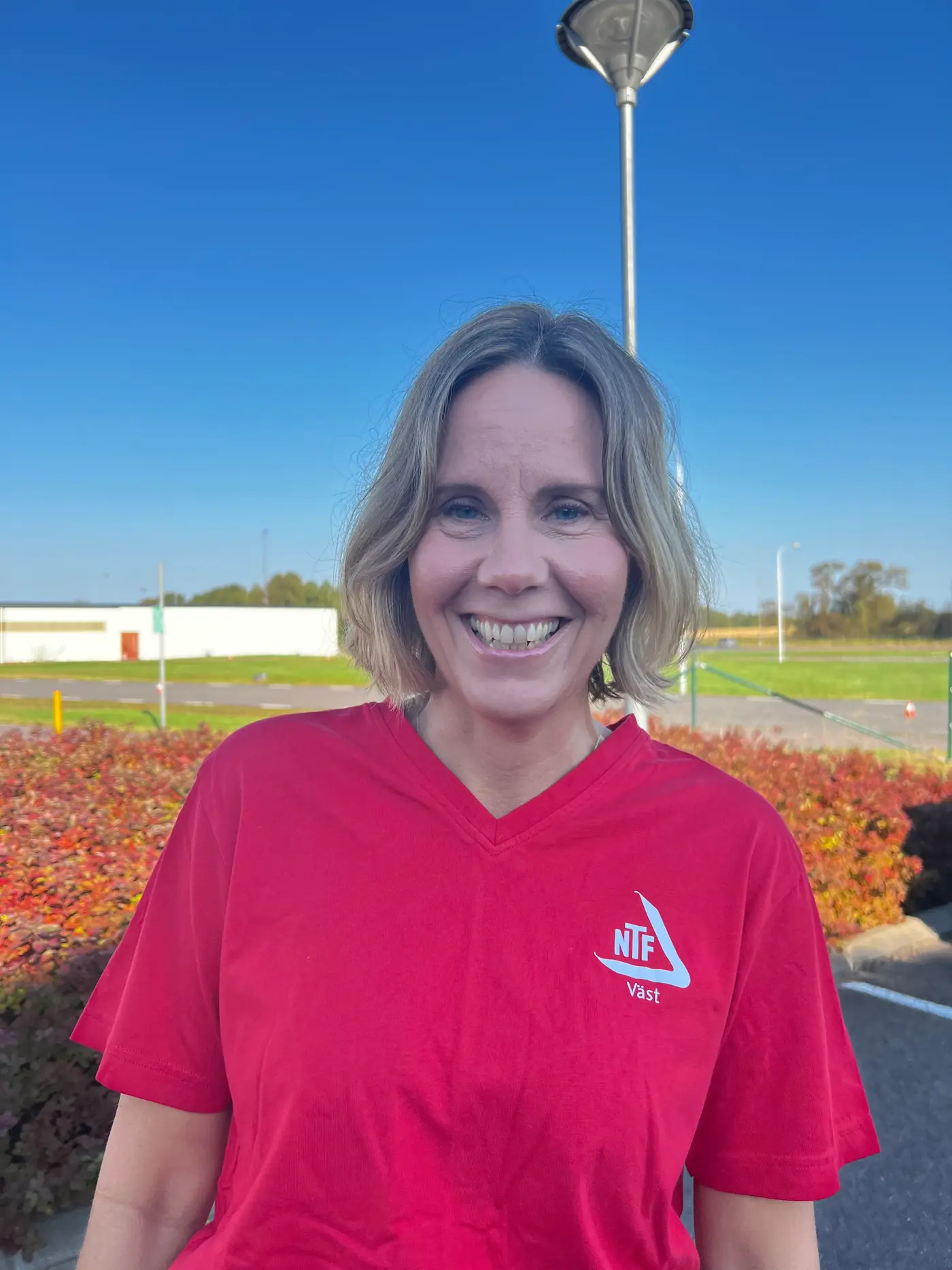 En leende kvinna med axellångt hår och röd t-shirt.