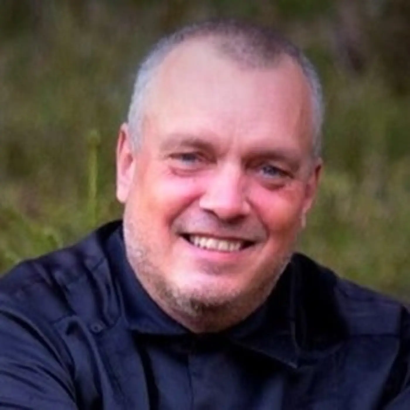 En leende man med mörk skjorta.