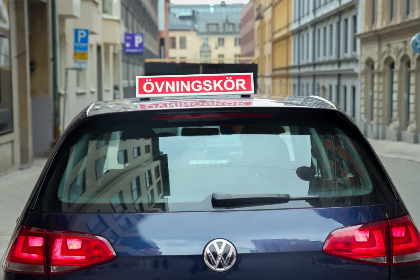 En bil med en övningskörningsskylt på taket.