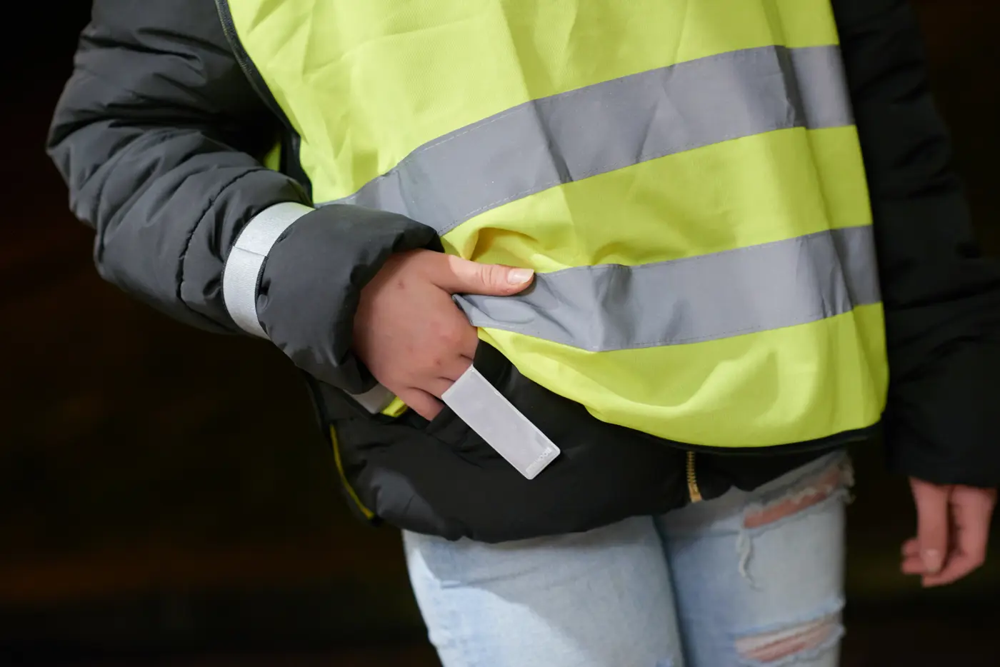 Närbild på person med reflexväst och reflexband runt armen.
