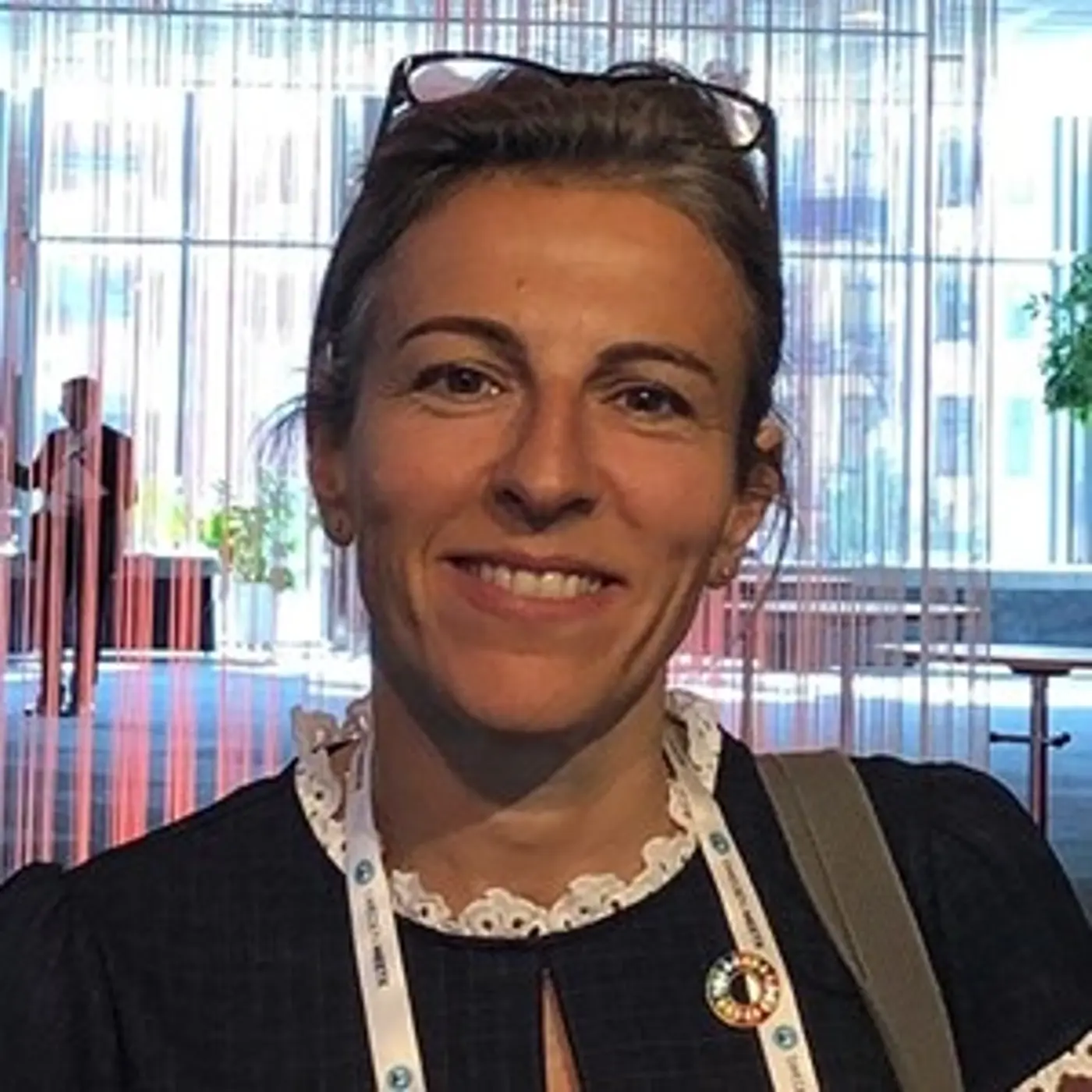 En leende kvinna med uppsatt hår och glasögon på huvudet.