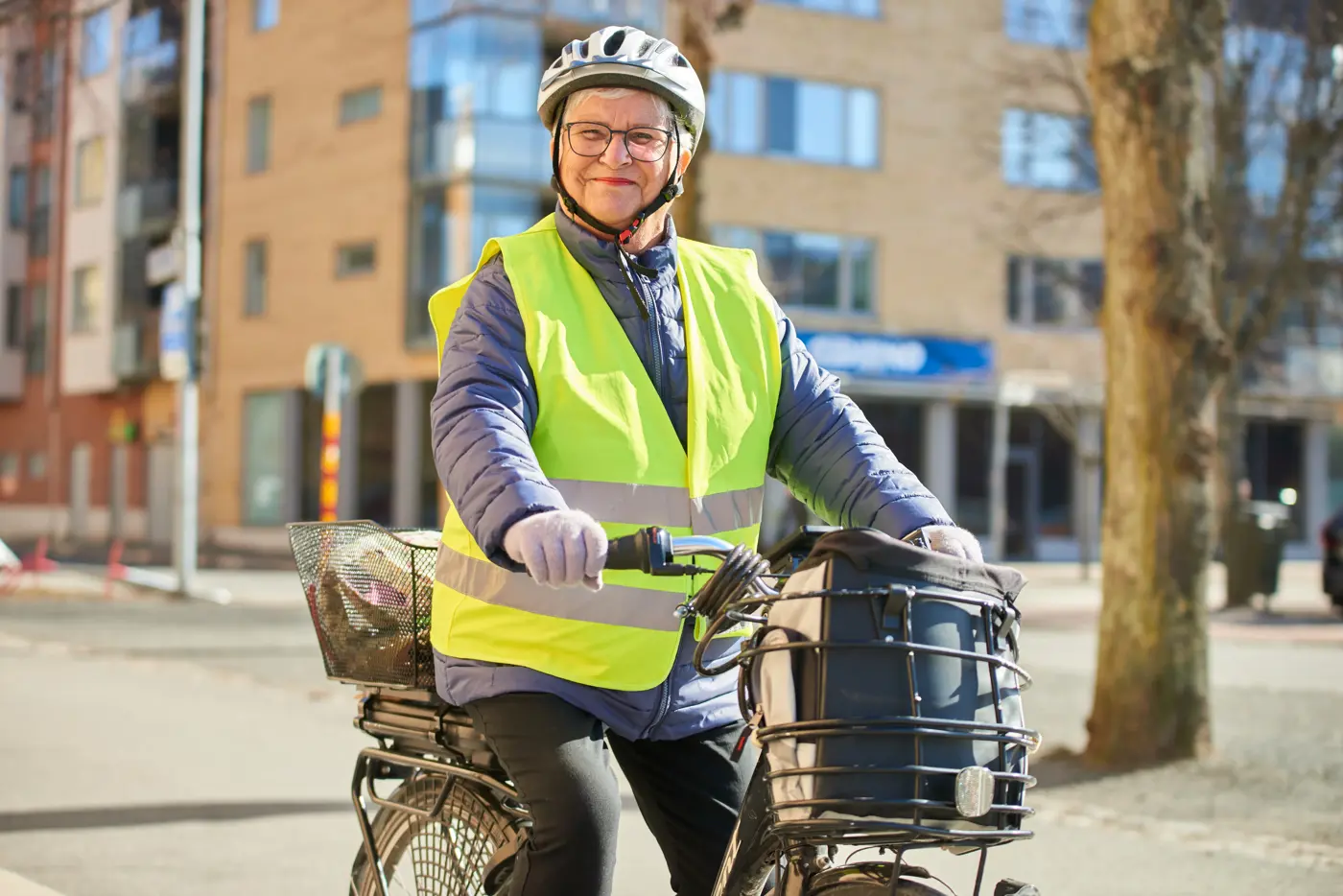 En äldre person cyklar med reflexväst och cykelhjälm