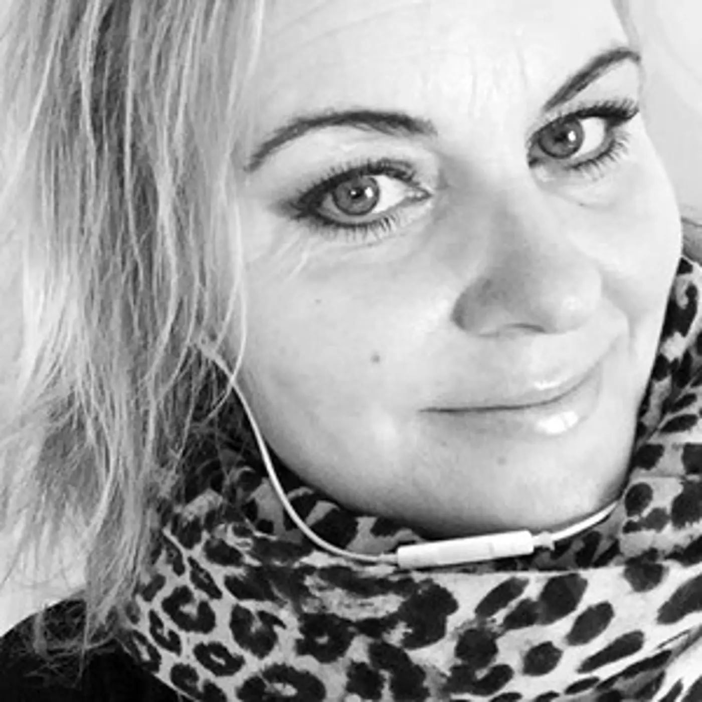 En leende kvinna med kort hår och leopardmönstrad scarf.