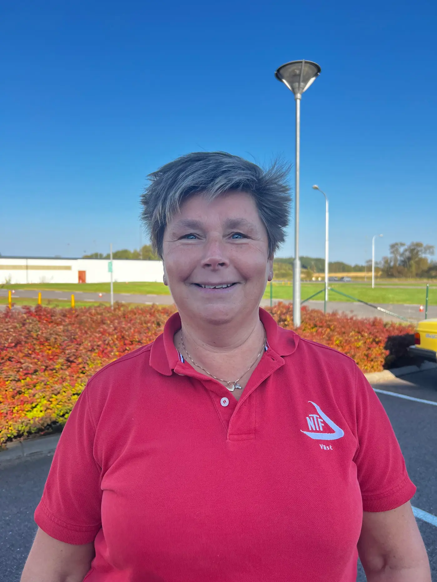 En leende kvinna med kort hår och röd t-shirt.