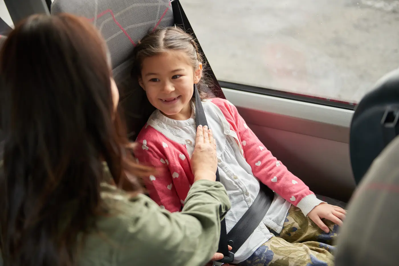 Ett barn får hjälp av sin mamma att knäppa sitt säkerhetsbälte i en buss