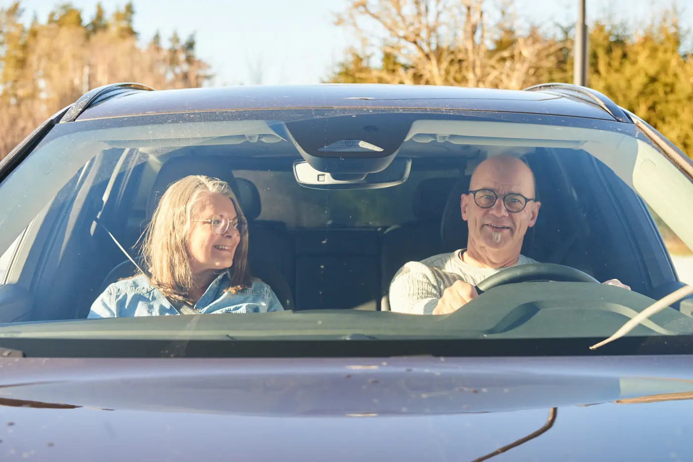 Två äldre personer, en man och en kvinna, sitter i en bil.