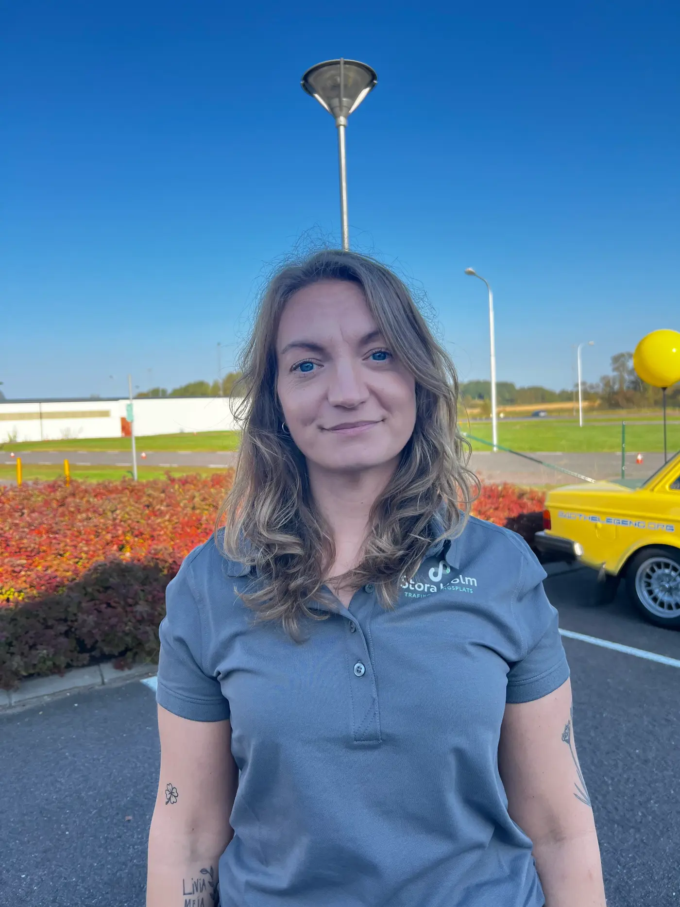 En leende kvinna med grå piké t-shirt.