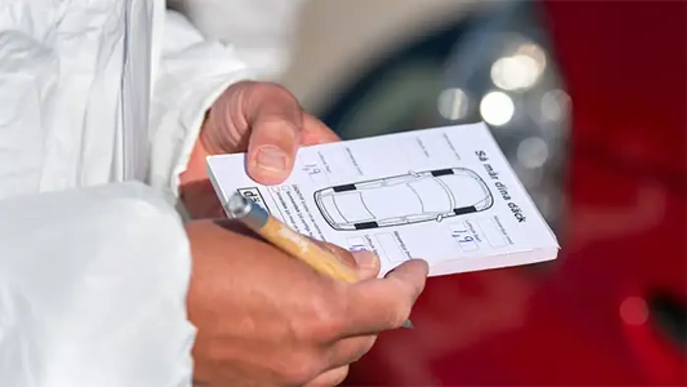 Ett par händer håller i ett protokoll för däckkontroll av personbil.