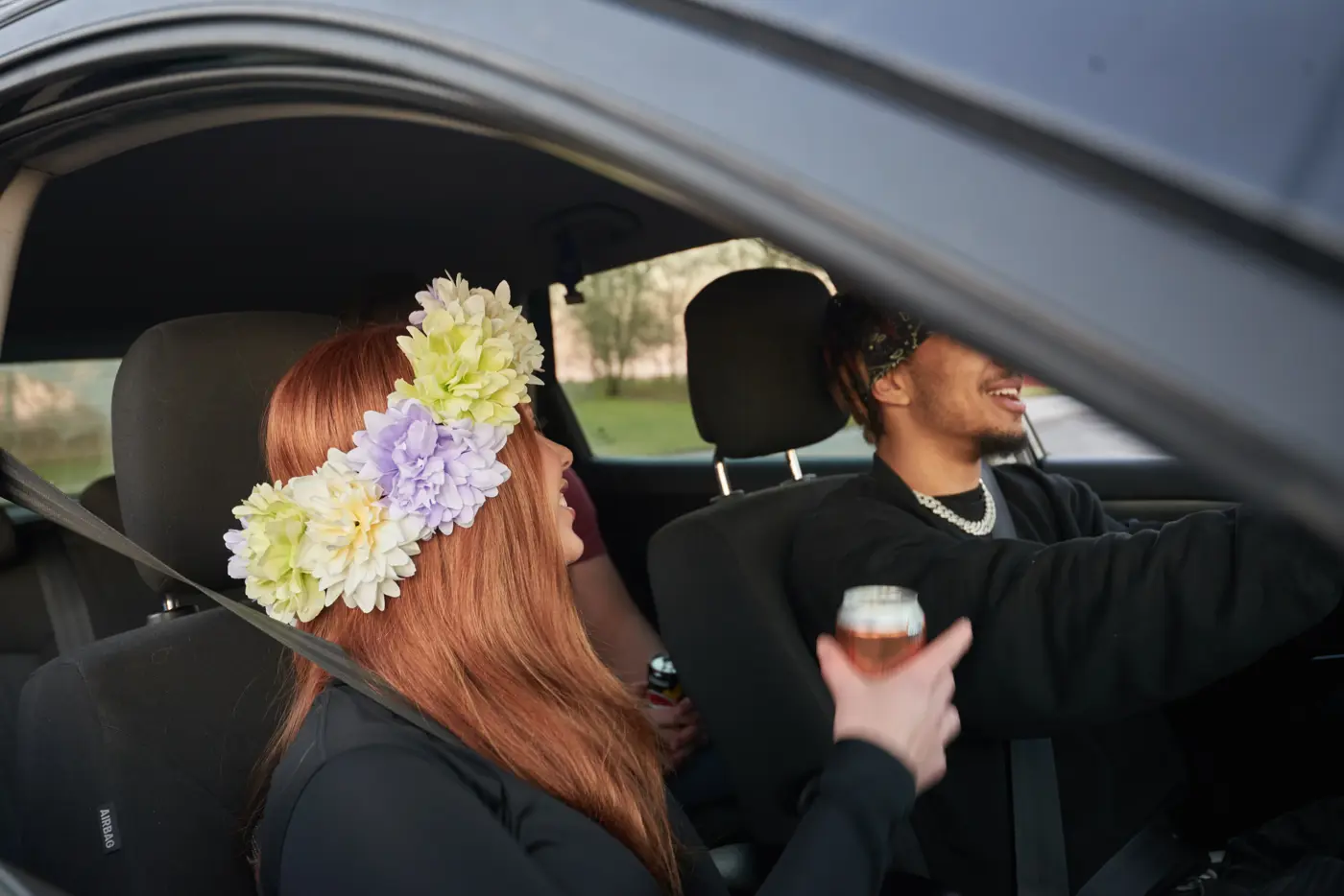 Tre ungdomar sitter i en bil. En av passagerarna dricker öl.