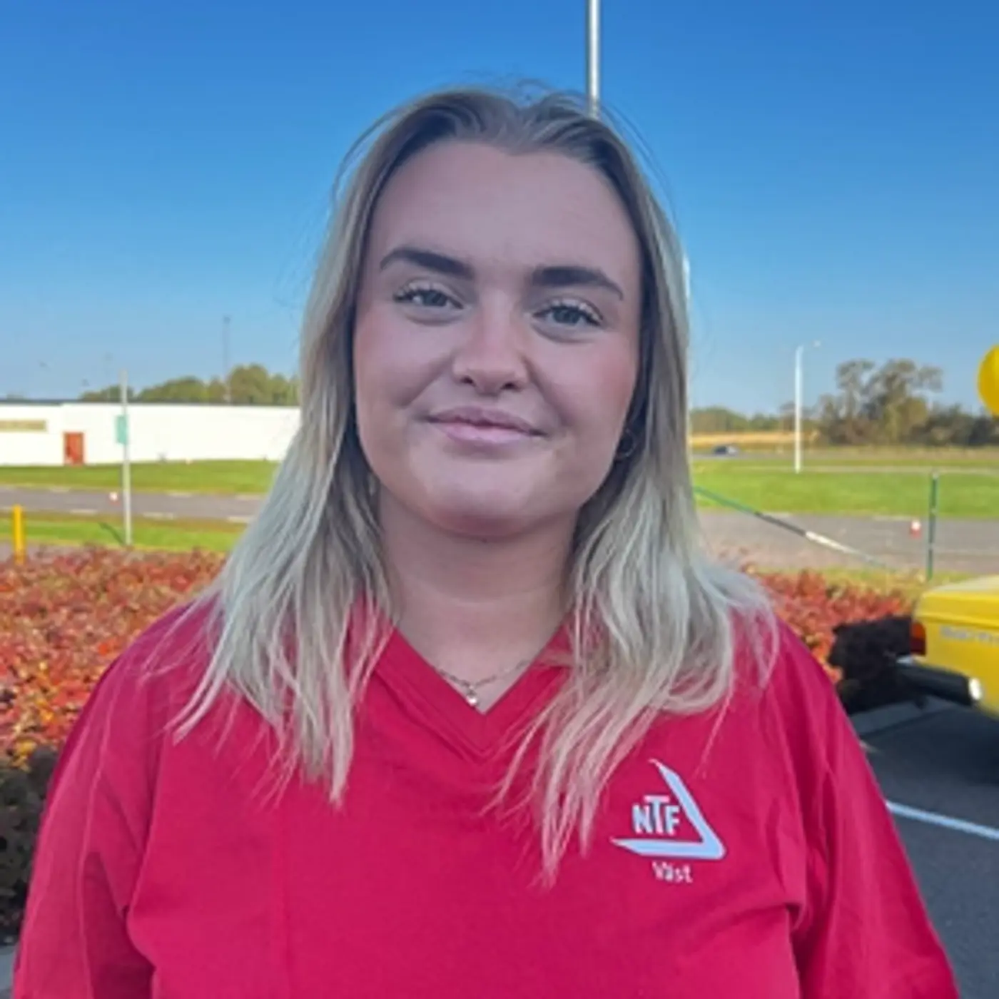 En leende kvinna med blont hår och en röd t-shirt.