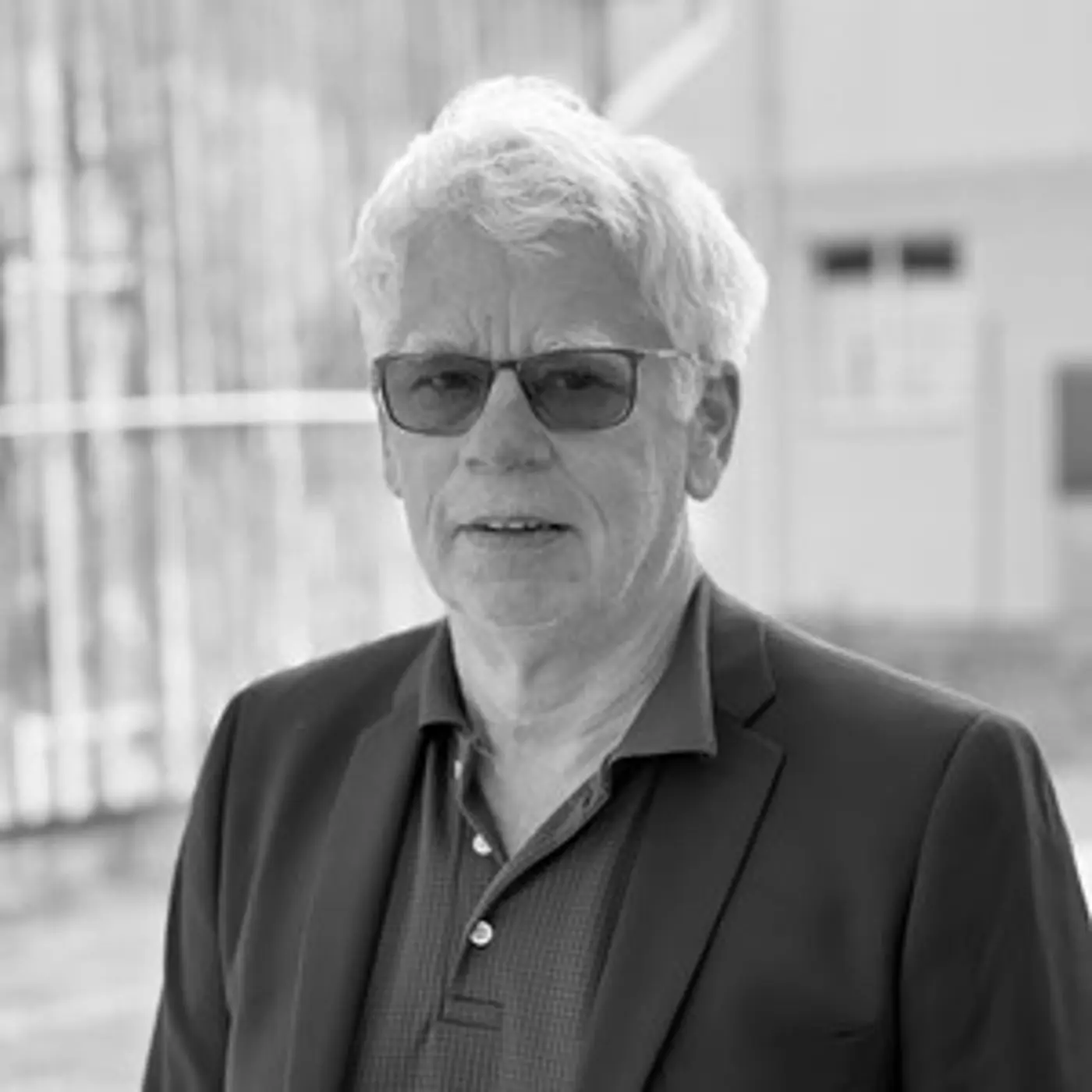 En äldre man med glasögon och kavaj.