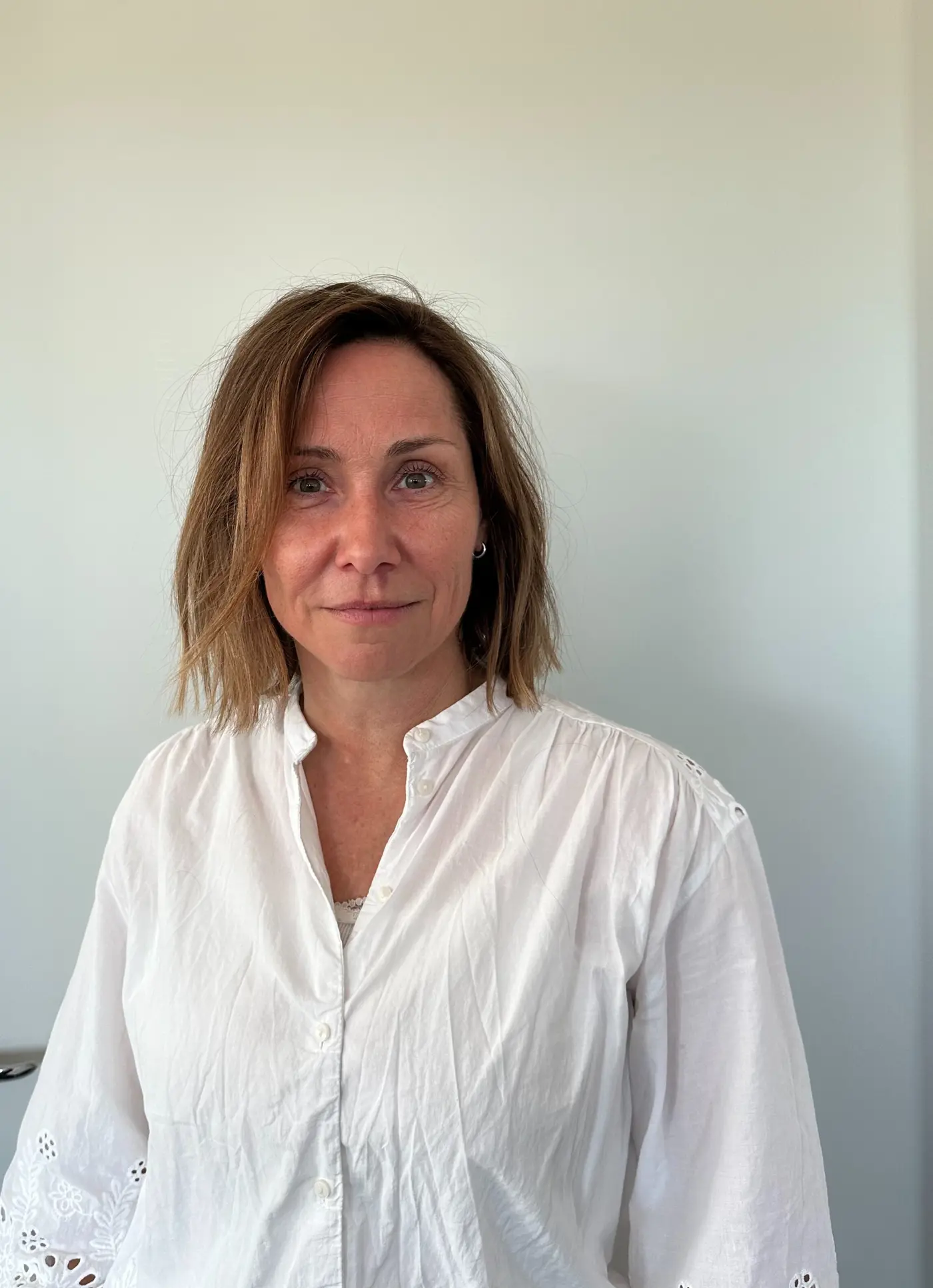 Porträttbild på en kvinna med axelkort hår och vit blus.