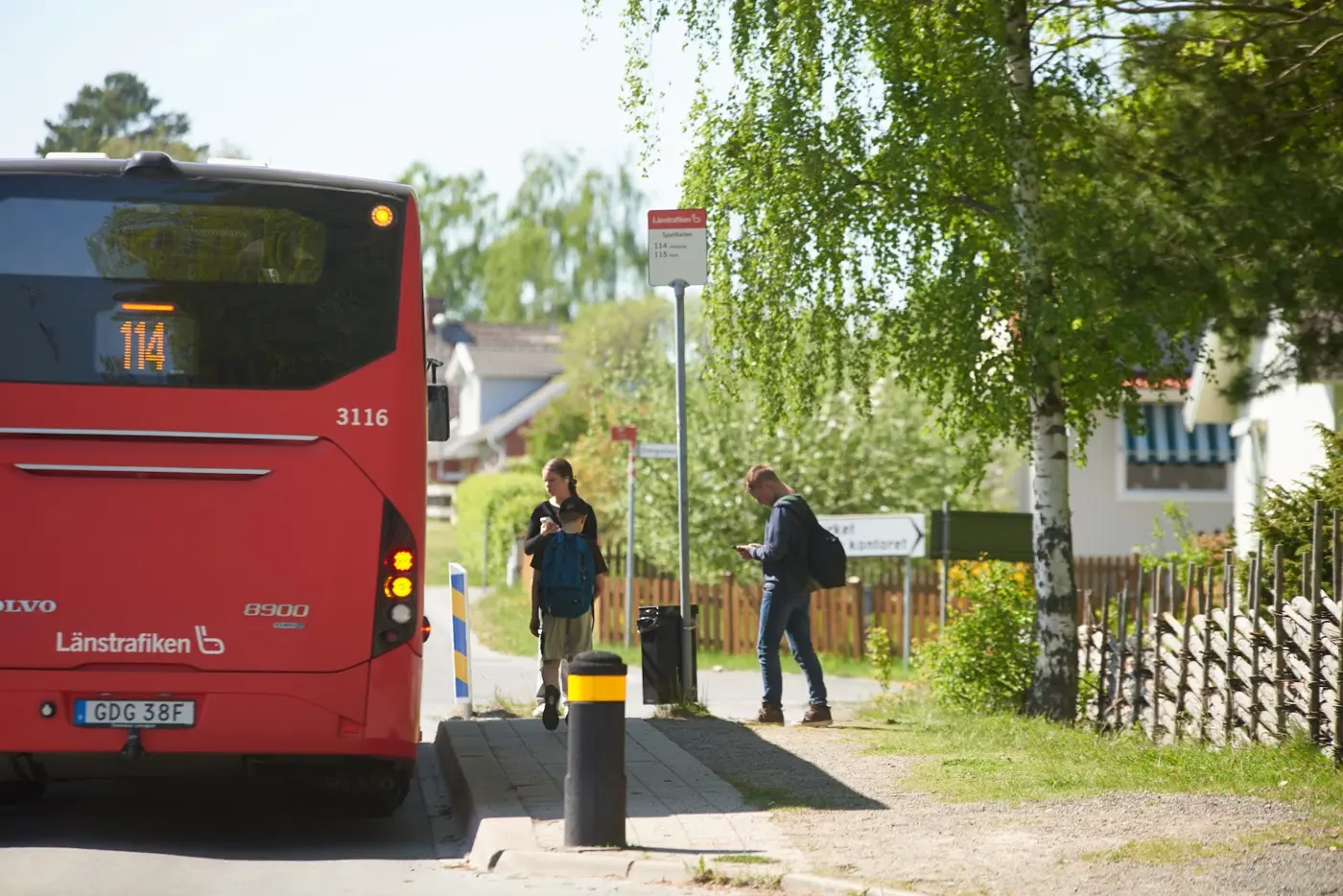 En buss blinkar in vid en busshållplats där skolbarn väntar på att få stiga på.