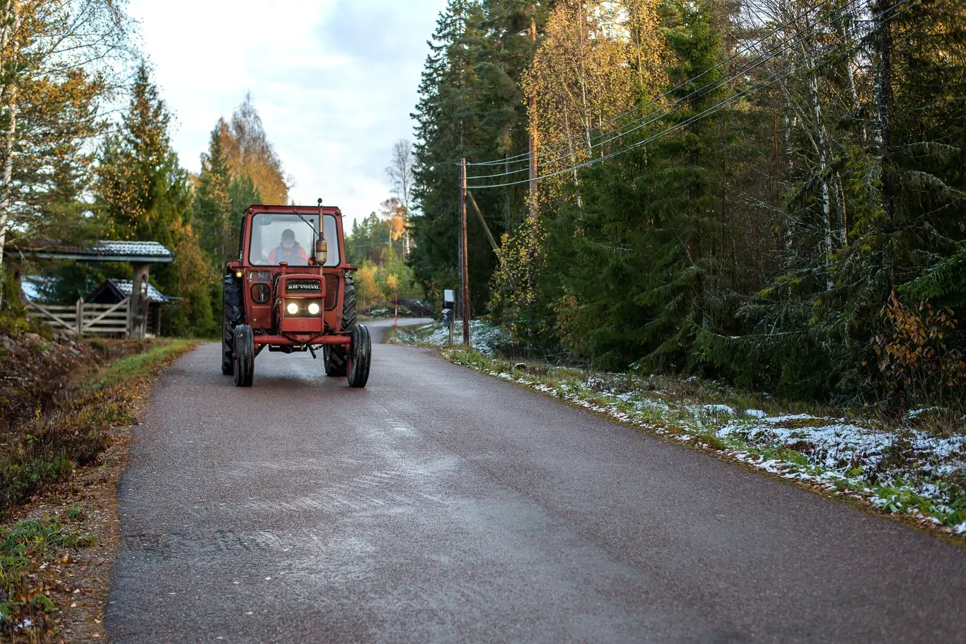 En traktor kör på en skogsväg. Bilden är tagen framifrån.
