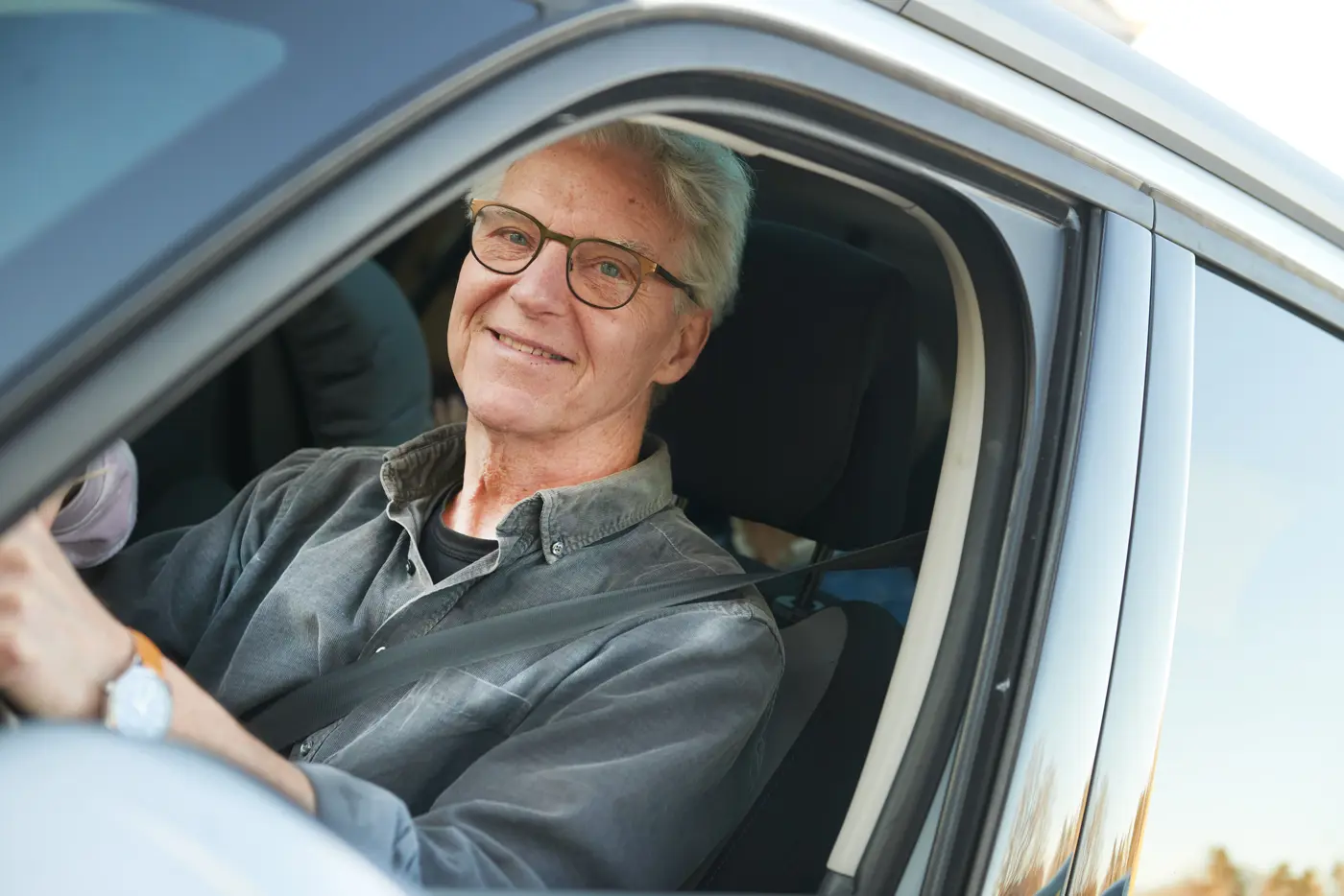 En äldre man kör bil.